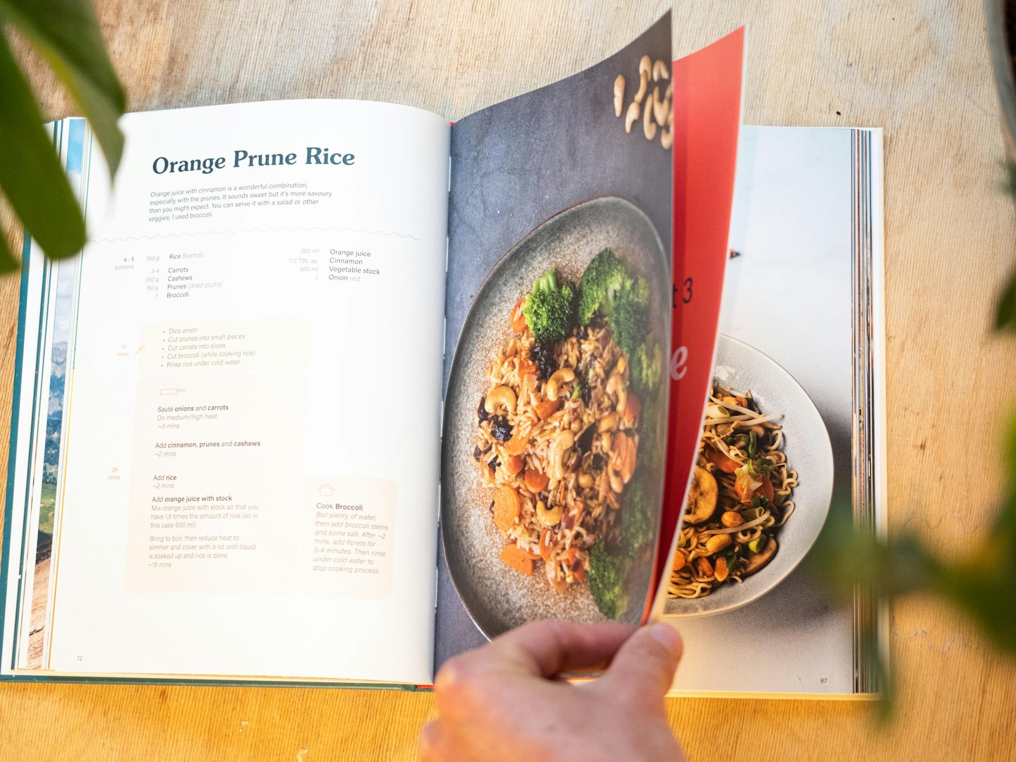 Mano che gira una pagina di un libro di cucina con una ricetta e un piatto.