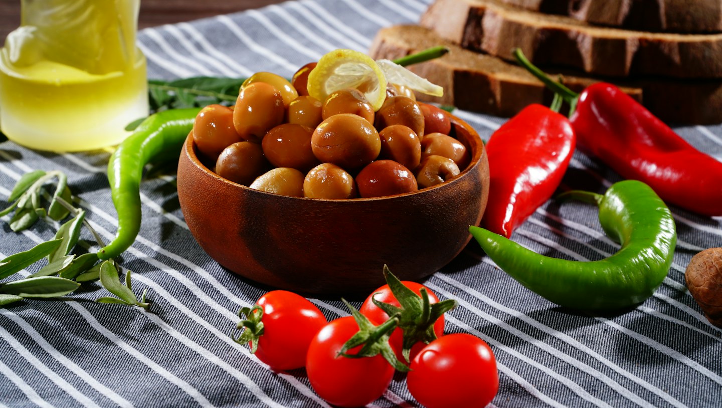Ingredienti mediterranei freschi disposti su una tovaglia a righe.
