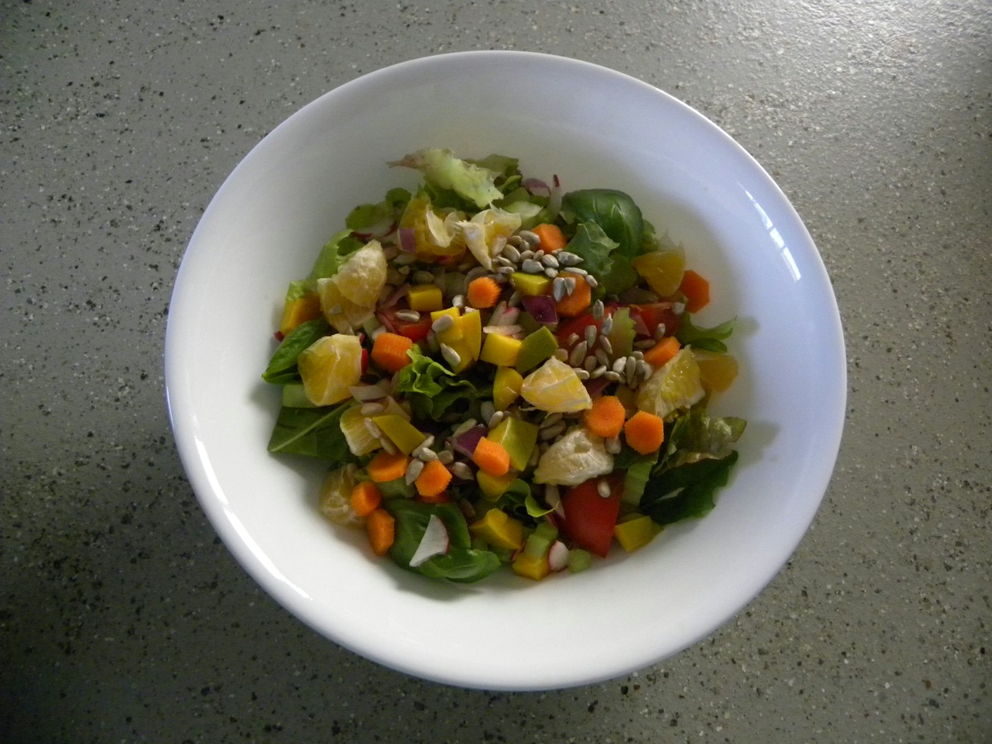 Una ciotola di insalata colorata su un bancone screziato.
