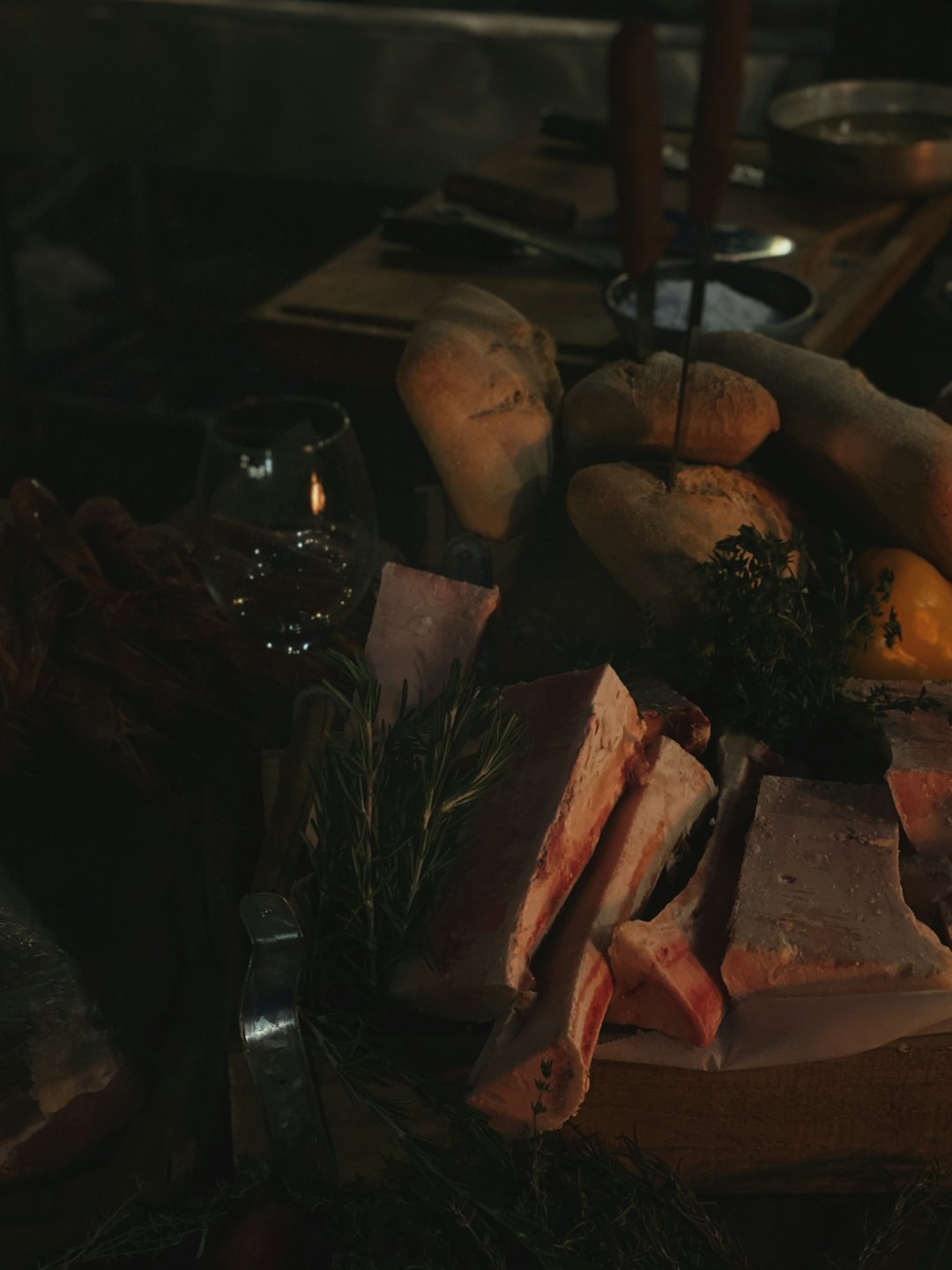 Tagli di carne cruda con erbe aromatiche e pane su un tavolo di legno.